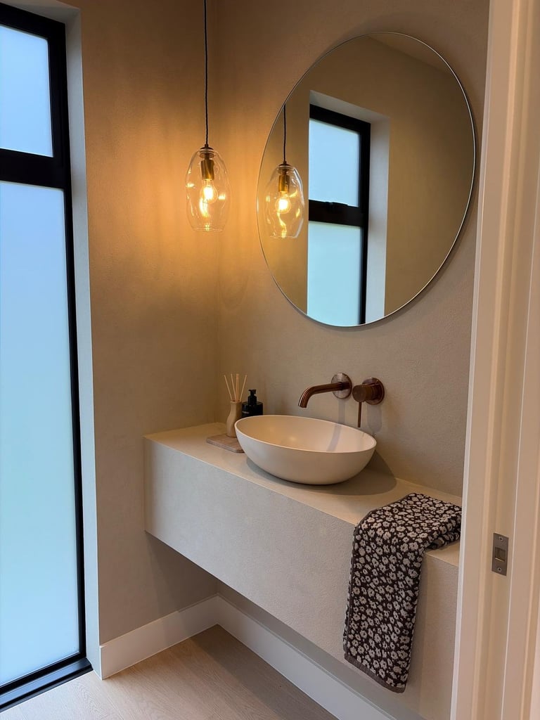 Modern bathroom with white floating vanity, round mirror, pendant lights, and vessel sink near large window