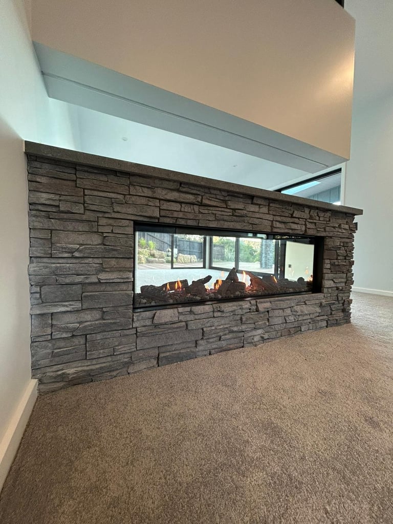 Modern living room with a linear gas fireplace insert in a dark stone accent wall, white ceiling detail, and carpet flooring